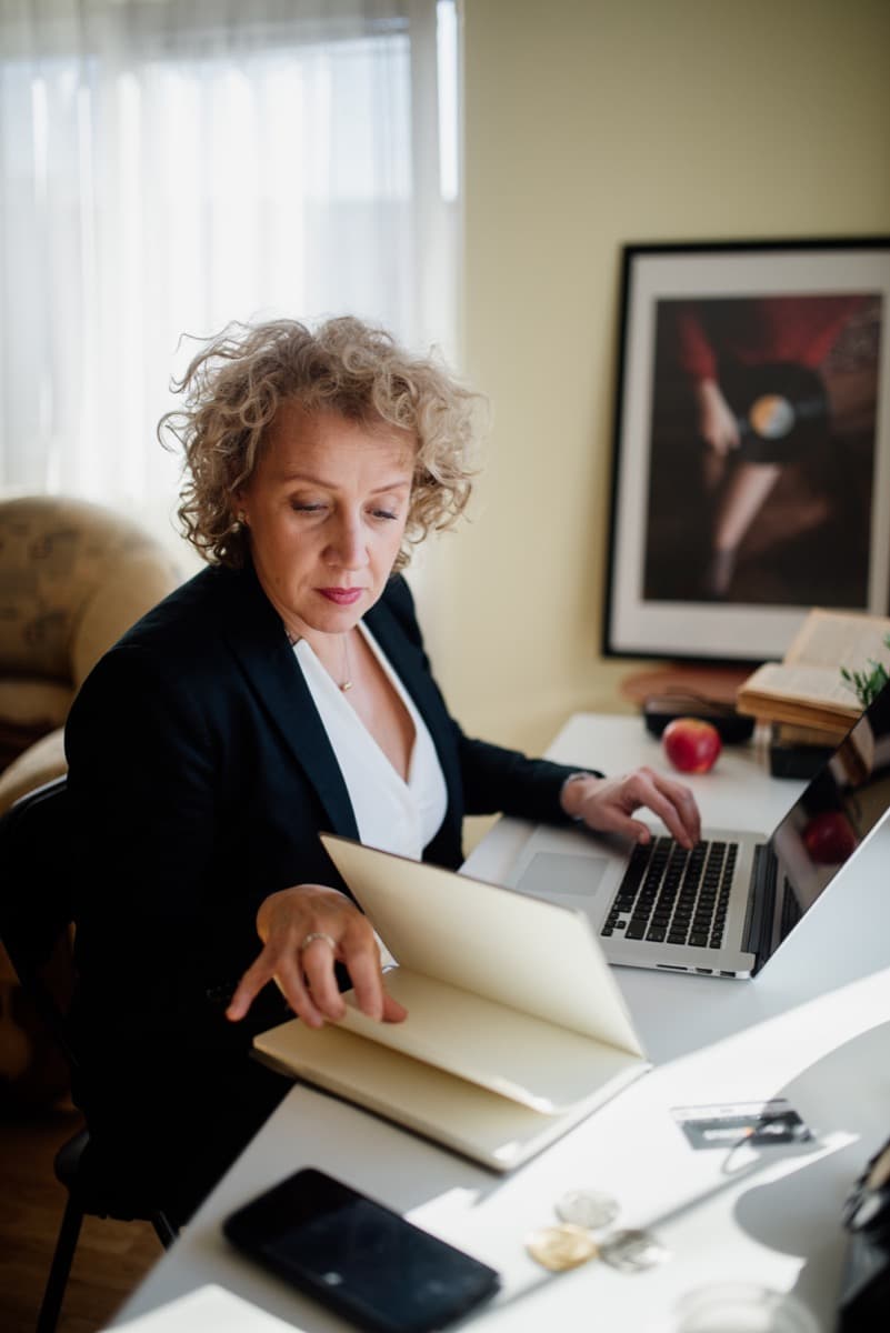 A professional reviewing documents and a laptop at a desk